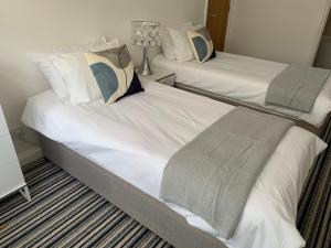 2 bedden met witte lakens en kussens in een kamer bij Villa Levante in Paignton