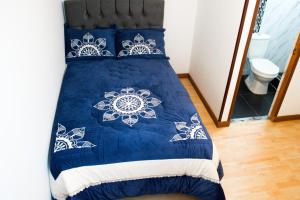 a bed with a blue and white comforter at Hostal Lucas Corferias - Habitaciones Privadas in Bogotá