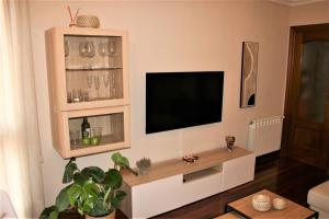 sala de estar con TV de pantalla plana en la pared en El Fuste, en Oviedo