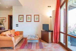 ein Wohnzimmer mit einem Sofa und einem TV in der Unterkunft Madonna della Rosa in Chianciano Terme