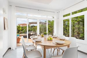 Un comedor con una mesa y sillas blancas. en Villa Cau Ventos, en Cala Galdana