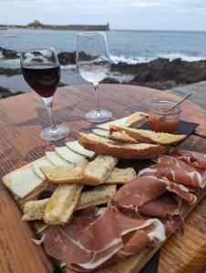un piatto di carne e formaggio e due bicchieri di vino di La perle de Collioure à 100 métres de la plage de sable fin avec piscine et parking a Collioure