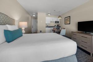 1 dormitorio con 1 cama blanca grande y TV de pantalla plana en Pelican Shores Inn, en Lincoln City