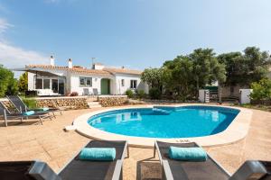 a swimming pool with lounge chairs and a house at Villa Cau Ventos in Cala Galdana
