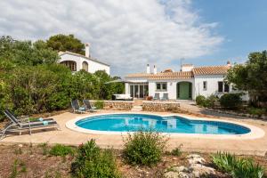 una villa con piscina frente a una casa en Villa Cau Ventos, en Cala Galdana