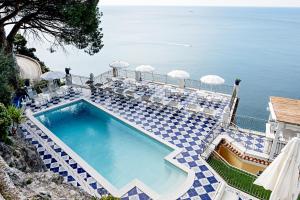 ein Swimmingpool mit Stühlen und das Meer im Hintergrund in der Unterkunft Hotel Villa Pandora in Maiori
