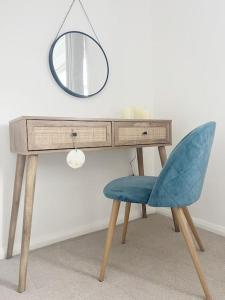 een bureau met een spiegel en een blauwe stoel bij Field House in Boroughbridge