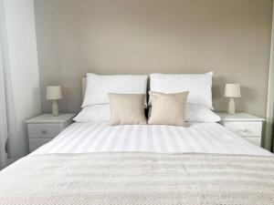 een wit bed met witte kussens en 2 lampen bij Field House in Boroughbridge