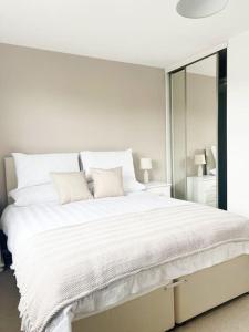 een witte slaapkamer met een groot wit bed met spiegels bij Field House in Boroughbridge