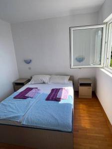 a bedroom with a bed with purple sheets and a window at The View Sveti Stefan V2 in Sveti Stefan