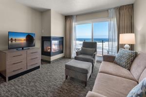 uma sala de estar com uma televisão, um sofá e uma cadeira em Pelican Shores Inn em Lincoln City