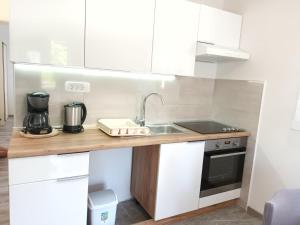 a kitchen with white cabinets and a sink at Miljenko&Miljenka in Supetarska Draga