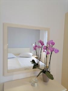 a vase with flowers on a table in front of a mirror at Miljenko&Miljenka in Supetarska Draga