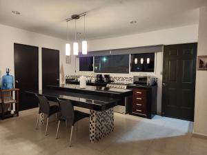 uma cozinha com um grande balcão preto e cadeiras em Pergola´s Road House em Yalsí