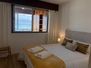 Un dormitorio con una cama grande con ventana. en Precioso piso en Baiona con vistas al mar, en Baiona