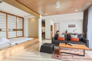 a bedroom and a living room with a bed and a couch at Eastin Tan Hotel Chiang Mai in Chiang Mai