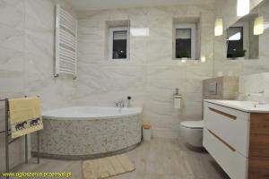 biała łazienka z wanną i toaletą w obiekcie Apartamenty Pod Fortami w mieście Przemyśl