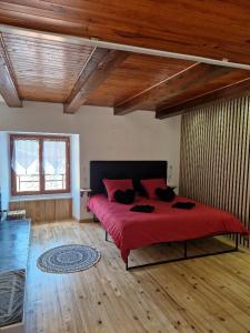 Schlafzimmer mit einem roten Bett und Holzboden in der Unterkunft La parenthèse coquine in Saurier