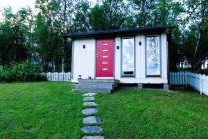 una pequeña casa con una puerta roja en un patio en Aurora Cabin, en Kiruna