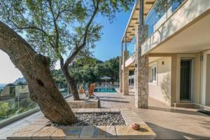 a house with a tree in the middle of a courtyard at Villa with sea view Kontogialos Greece in Kontogialos