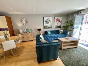 a living room with a blue couch and a table at Stunning 2-bed Town Centre Apartment - Hosted by Hutch Lifestyle in Leamington Spa