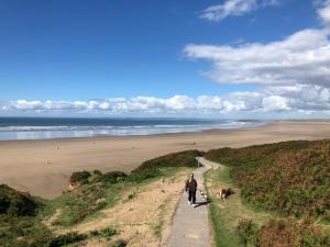 um homem a caminhar por um caminho ao lado de uma praia em Ger Tŷ em Swansea