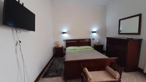 een slaapkamer met een bed en een flatscreen-tv bij CASA VACANZE NONNA ROSETTA in Menfi