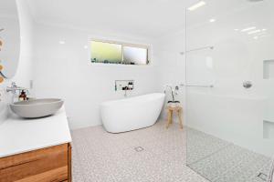 a white bathroom with a tub and a sink at La Casa Bella in Gerringong +10 photos