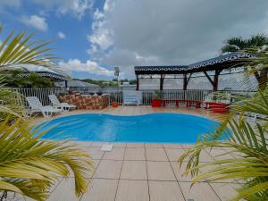 a swimming pool with chairs and a table and a fence at Résidence Le Palmier Royal in Sainte-Rose