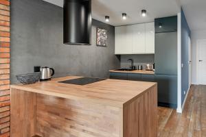 a kitchen with a wooden island in the middle at Rezydencja Wintera by Grand Apartments in Gdańsk