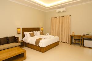 una camera da letto con un letto, un divano e una televisione di Syailendra Hotel Syariah a Jepara