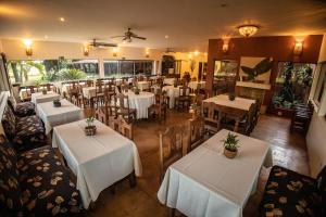 an empty restaurant with white tables and chairs at Paineiras Hotel Fazenda in Uberaba