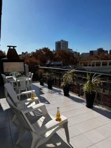 un patio con sillas blancas y botellas de cerveza. en 2 amb Con rooftop y parrilla propia en Buenos Aires