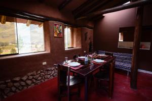 a dining room with a table and some windows at Rumi Lodge Pisac in Pisac