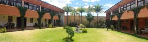 une cour d'un bâtiment avec des arbres et de la pelouse dans l'établissement Hotel Ollin Teotl, à San Juan Teotihuacán