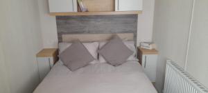 Bett mit weißer Bettwäsche und Kissen in einem Zimmer in der Unterkunft Luxury spacious family caravan in Edinburgh