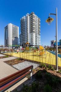 a park with a bench and a playground with tall buildings at Apartament Modern w Albatross Towers Gdańsk in Gdańsk