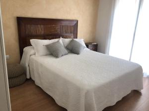 una camera da letto con un grande letto bianco con cuscini di Casita de la playa a Palamós