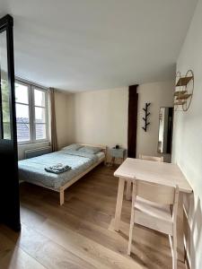 Un dormitorio con una cama y una mesa. en Appartement bords de l’Eure charmant studio en Chartres