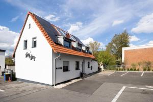a white building with an orange roof in a parking lot at House by StayStay I 24 Hours Check-In in Nuremberg
