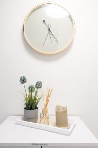 une horloge sur une étagère avec des plantes et des fleurs dans l'établissement House by StayStay I 24 Hours Check-In, à Nuremberg