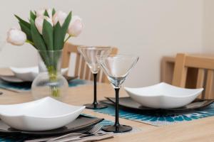 a table with wine glasses and flowers on it at Cozy Apartment Batalionów Chłopskich in Gdynia by Renters in Gdynia