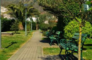 rząd zielonych ławek w parku w obiekcie Hocevar apartment w mieście Herceg Novi