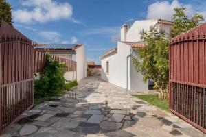 un chemin en pierre entre deux bâtiments avec une clôture dans l'établissement Casa do Moleiro, à Caldas da Rainha