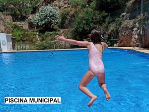 a woman in a bathing suit jumping into a swimming pool at LIGNUM Casa Rural in Ayna