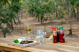 a wooden table with plates of food and glasses of wine at Nsunge Nsunge Farm and Natural Resort in Lusaka