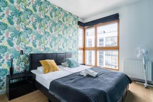- une chambre avec un lit et un papier peint floral dans l'établissement Hallera by Loft Apartments, à Gdańsk