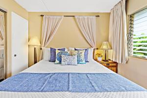 a bedroom with a large bed with blue pillows at Kihei Kai Nani 368 in Kihei +17 photos