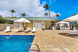 a pool with chairs and umbrellas next to a house at Kapalua Bay Villa 33G4 in Kahana