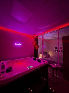 Cette chambre dispose d'une grande baignoire avec des lumières violettes. dans l'établissement CocoonSPA LoveRoom Jacuzzi, à Toulouse